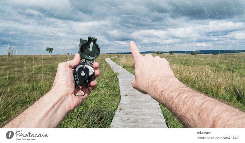 POV image of traveler man holding a compass and pointing direction in the landscape. pov orientation hand people lifestyle orienteering view adventure