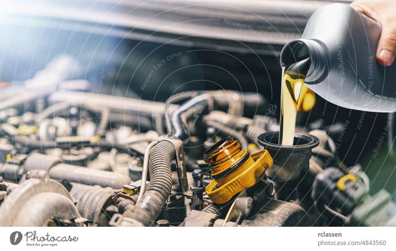 Pouring oil to car engine. Fresh motor oil poured during an oil change to a car. lubricant petroleum auto automobile automotive bottle container diesel