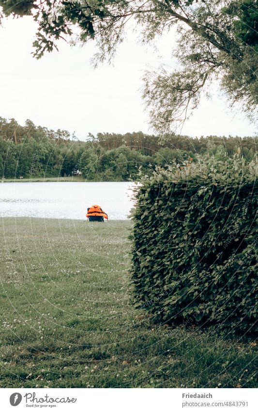 Orange backpack on a quiet corner on the shore of the lake Lake Meadow Hedge Grass Backpack forsake sb./sth. Doomed Loneliness Water bathe Refreshment