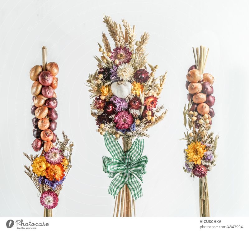 Pretty onion and  garlic braids with dried flowers at white background. pretty onion braids flowers braids seasonal autumn farmers concept front view bouquet