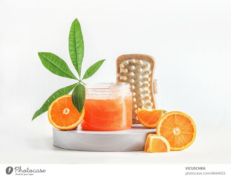 Body care setting with orange sugar scrub, sliced oranges, green leaf and massage brushes at white background. body care healthy skin care products