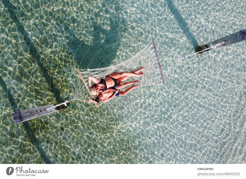 Mother and son relaxing on a hammock over the water. Air view. adult aerial beach beautiful caucasian child childhood coastline daughter enjoy enjoying exotic