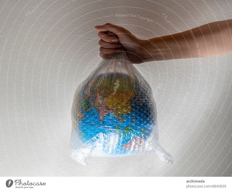 Hand holds a globe wrapped in plastic bubble wrap care change climate close up concept conceptual conservation earth environment environmental green hand impact