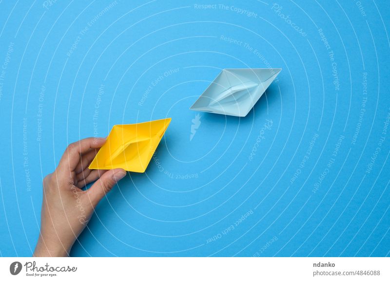A woman's hand holds a yellow paper boat, next to it is blue. support concept ukraine palm feminine sympathy unity symbol freedom national peace ukrainian