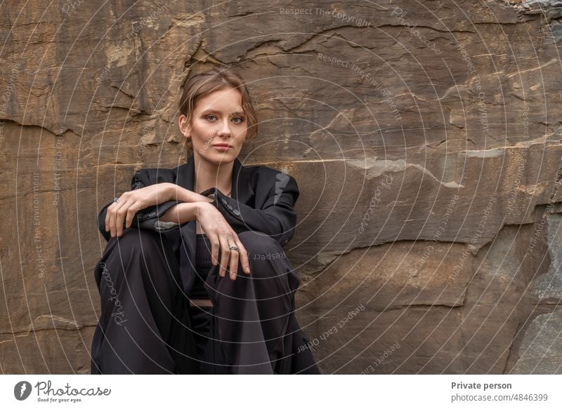 Business concept Pretty Caucasian woman in a business suit sits near a stone wall with copy room Woman Businessman more adult call Businesswoman Europe women