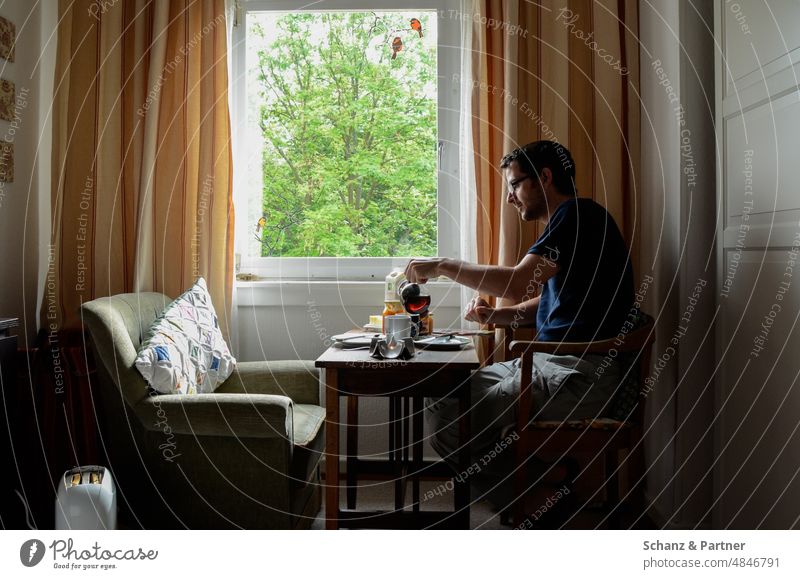 Man sitting at window eating breakfast alone Window at home Breakfast Eating Armchair Cozy relaxed by oneself Lonely Drape Vantage point person Quarantine
