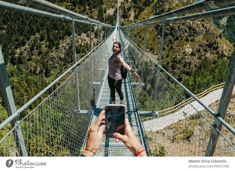 Young latin woman ison the longest Tibetan bridge in Europe, 600 meters long and 200 meters high in the Parish of Canillo in Andorra adventure alps andorra