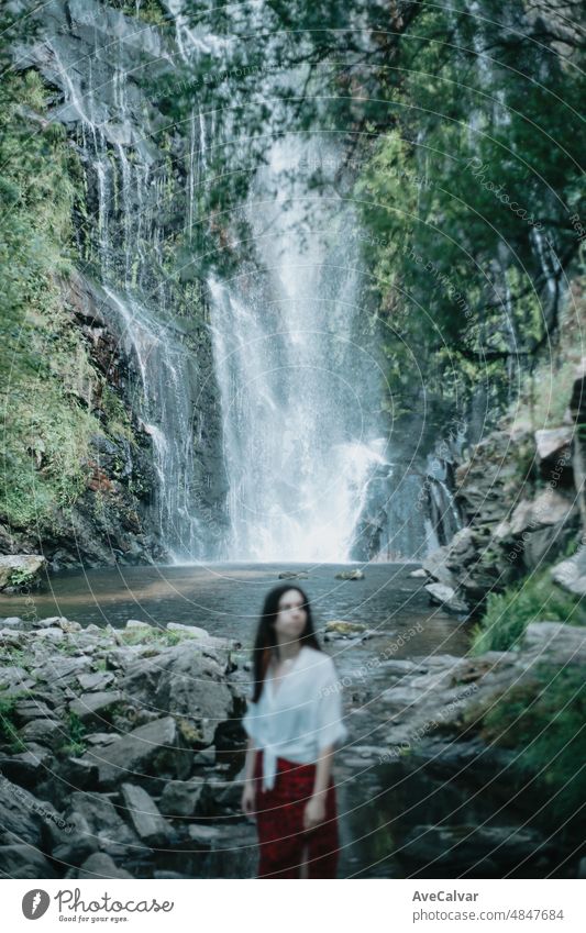 Out of focus frontal portrait young woman resting and looking a waterfall, meditation, yoga and thinking concepts. freedom in nature, independent lifestyle and freedom concept. Selective focus.