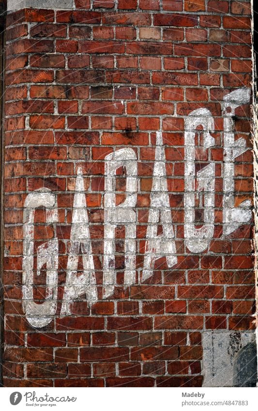 Old faded white lettering Garage in capitals on the old reddish brown brick wall of a car repair shop in the alleys of the old town of Bruges in West Flanders, Belgium