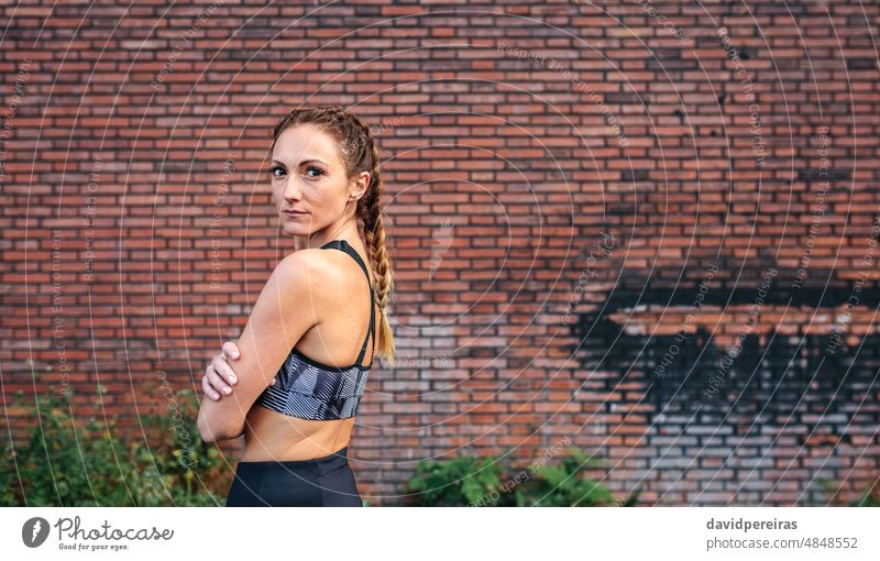 Sportswoman with boxer braids posing sportswoman brick wall looking camera sideways copy space waist up attractive empowerment adult top empowered background