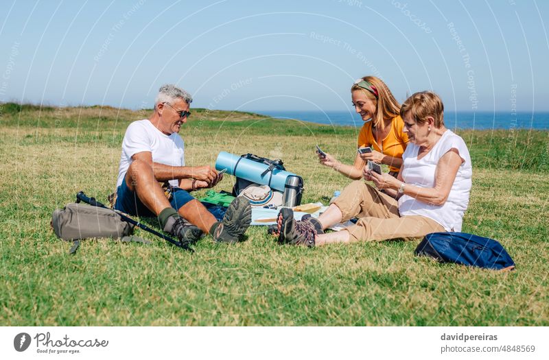 Adult family playing cards sitting on a blanket during an excursion adult together senior daughter smiling parent woman people happy poker outdoor mother father