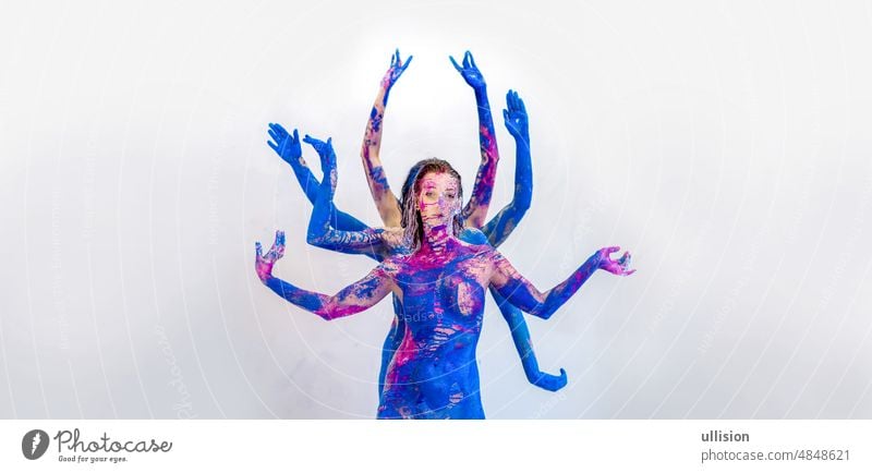 Many beautiful bodies of young artistic abstract painted women, with white, blue, pink and purple paint, stand behind each other and play with the arms the goddess Kali