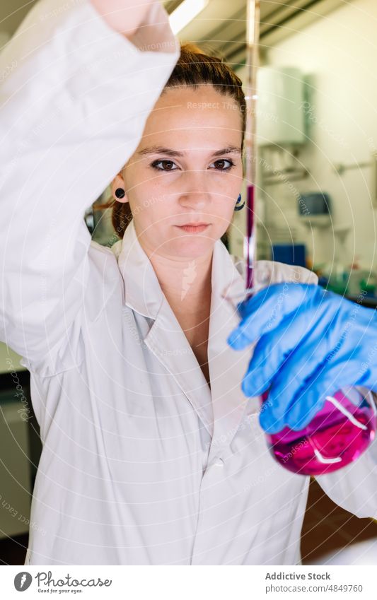 Chemist pouring liquid into flask in lab woman scientist laboratory chemical chemist experiment sample research expertise pharmacy science focus work test glove