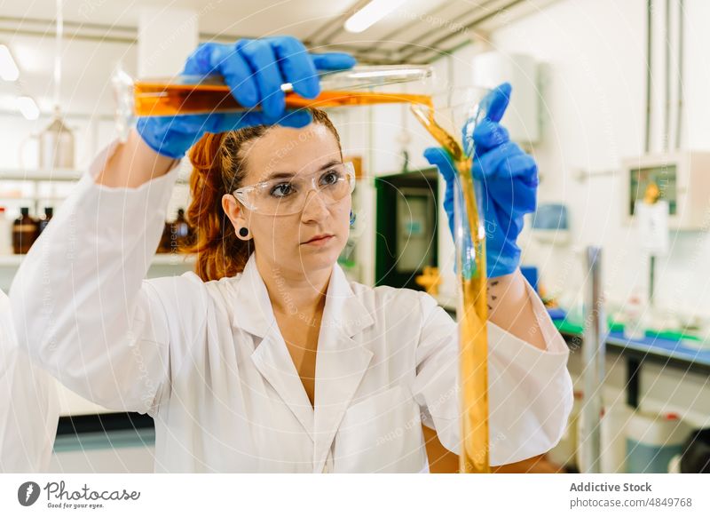 Concentrated scientist pouring chemical liquid in lab woman laboratory research chemist experiment test tube sample expertise science focus work glove