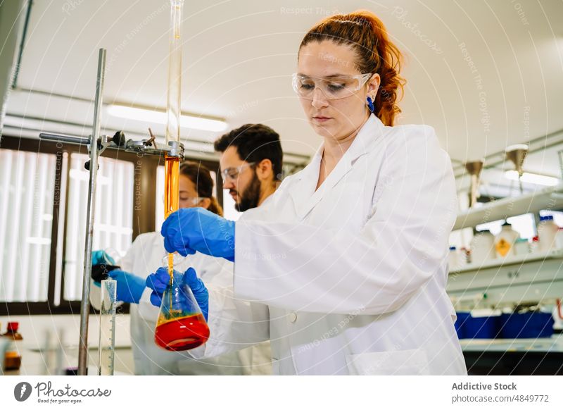 Scientists preparing chemical liquid in lab scientist research pour laboratory colleague scientific chemist experiment sample teamwork probe reagent coworker