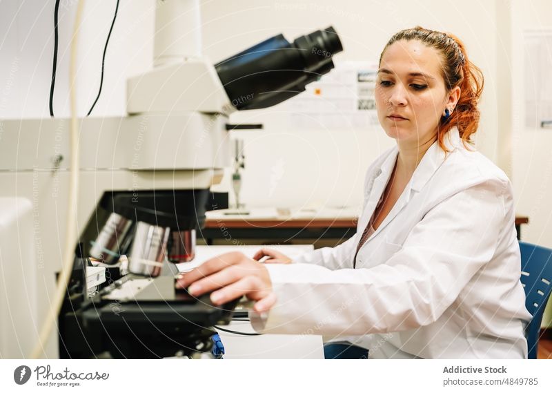 Chemist putting sample into microscope in lab woman chemist scientist laboratory experiment research analyze chemistry expertise science scientific focus work