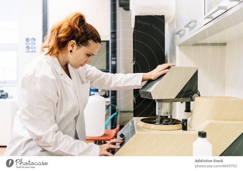 Concentrated scientist setting up modern equipment in lab woman laboratory set up operate chemist machine control apparatus diagnostic science work focus