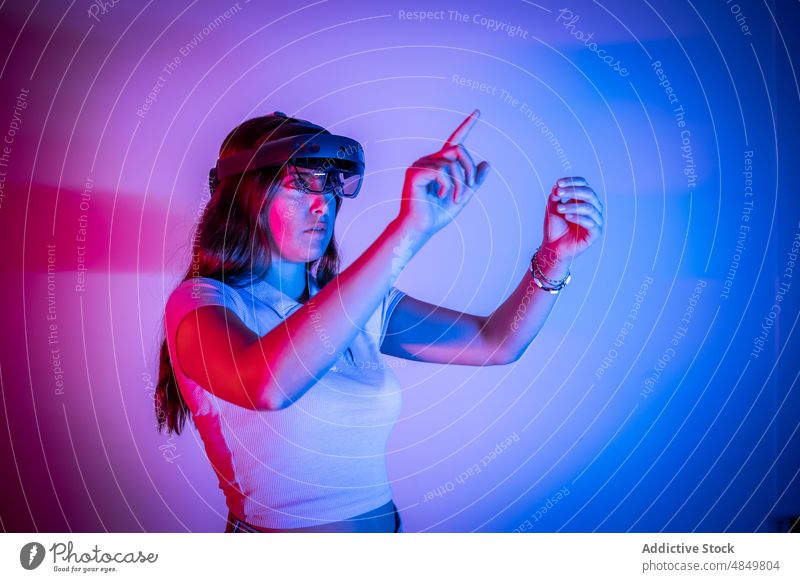 Woman in VR headset playing videogame woman vr cyberspace simulate futuristic virtual reality gamer augmented modern explore neon goggles innovation experience