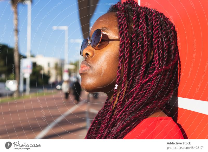 Serious young black woman in trendy outfit african portrait style female sunglasses african american red wall sunny serious modern confident fashion urban