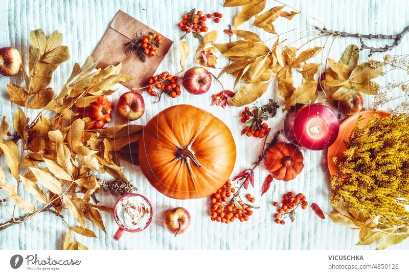 Autumn lifestyle with pumpkin,  envelope, yellow fall leaves, hot chocolate cup, candles and apples autumn white blanket backdrop seasonal flat lay background