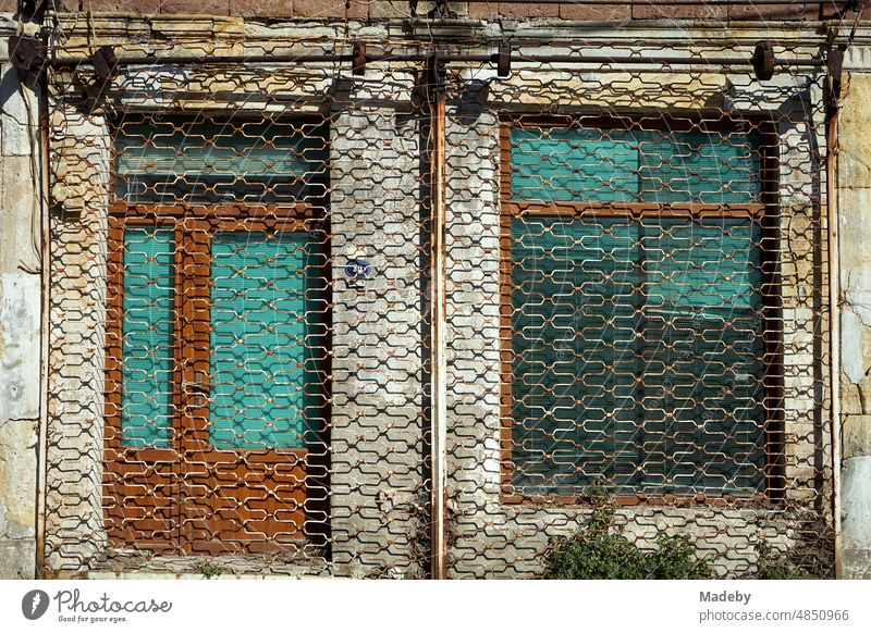 Rusty scissor grate in front of a closed store in summer sunshine in the old town of Foca on the Aegean Sea in Izmir province, Turkey commercial property