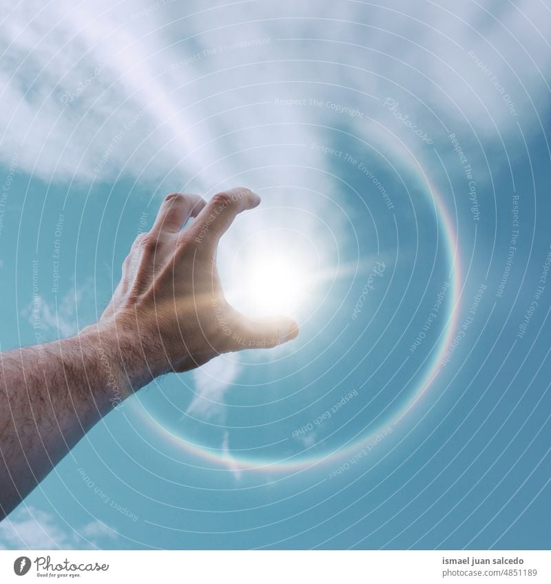 man hand un in the air playing with the sunlight arm fingers skin palm body part clouds sky blue touching feeling reaching pointing gesture gesturing concept