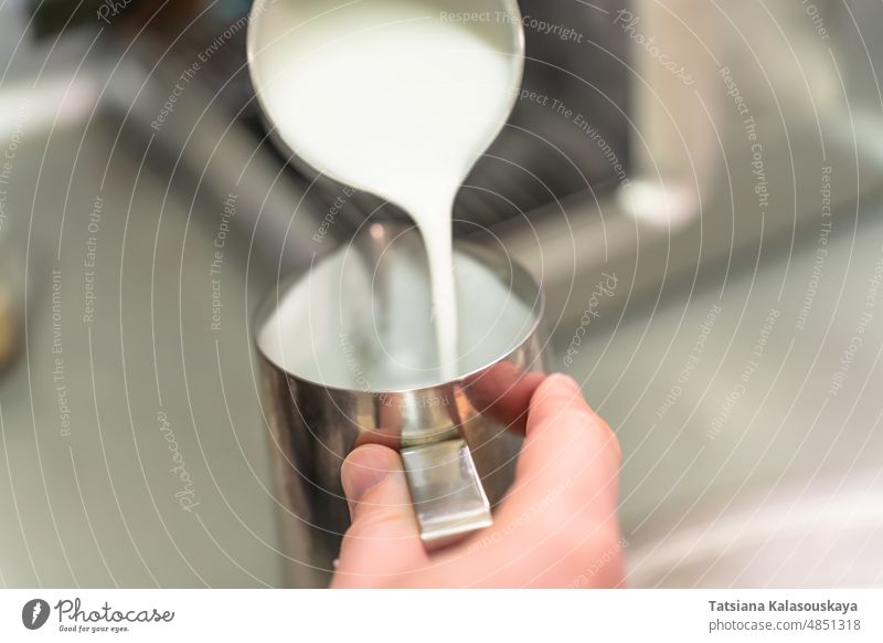 A barista pours whipped milk from one steel jug into another steamed milk cream Pitcher Jug Stainless Steel Dish Dishes utensil Container CupMug steam pitcher
