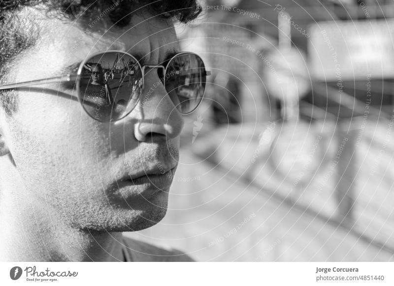 young man with sunglasses and his mother reflected in his sunglasses, in an amusement park. portrait person casual lifestyle leisure joy outdoors creativity