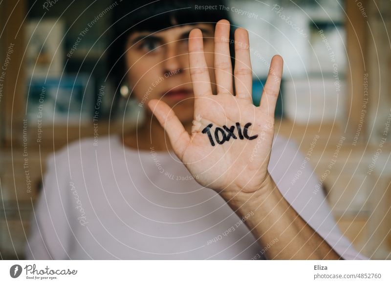 Woman holding her hand with Toxic written on it to camera toxic abusive Negative Behavior toxic masculinity Manipulation unpleasant relation Relationship Text