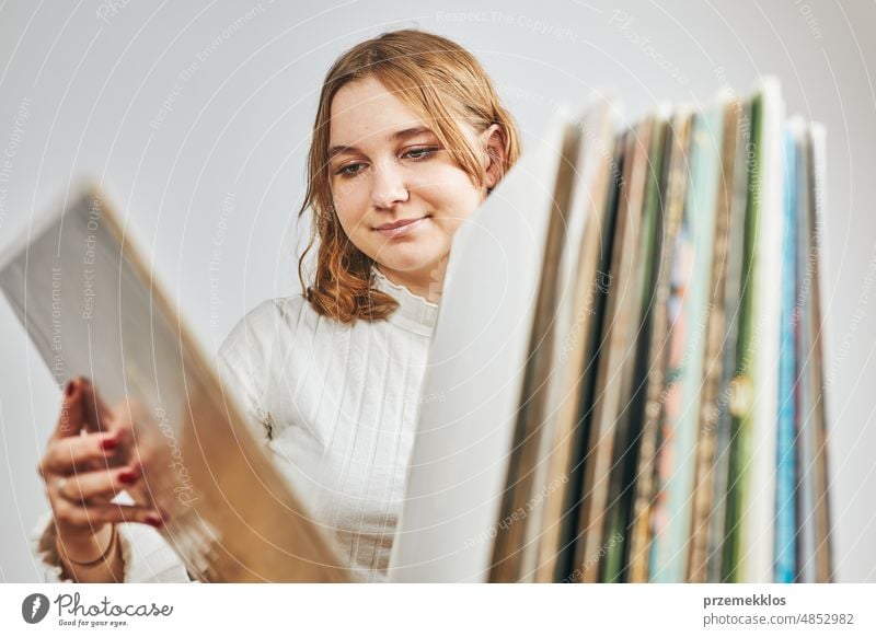 Playing vinyl records. Listening to music from vinyl record player. Retro and vintage music style. Young woman searching analog LP record album in stack of old records