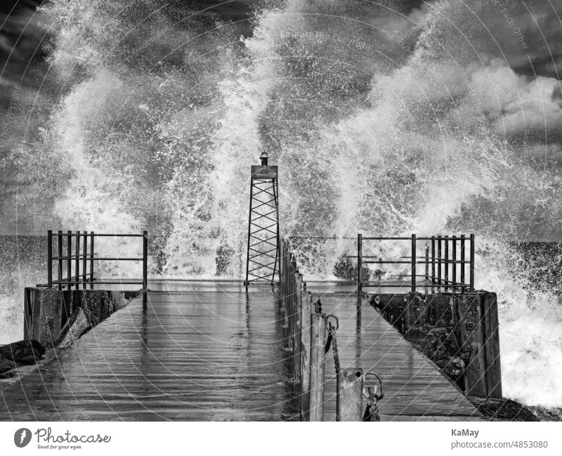 Black and white photo of lighthouse in swell with splashing waves on Danish North Sea coast of Vorupør Lighthouse Gale Waves Weather Hurricane Mole pier