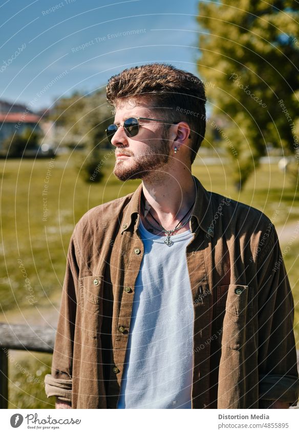 Trendy boy with sunglasses and a serious expression on a green meadow with copyspace facial expressions lifestyle professional gentleman caucasian casual