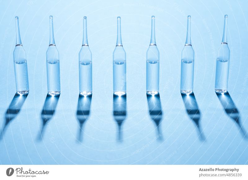 Ampules standing in a row on blue background. Medicine science ampoule ampule minimalism business care clinic close up concept corona coronavirus covid 19 cure