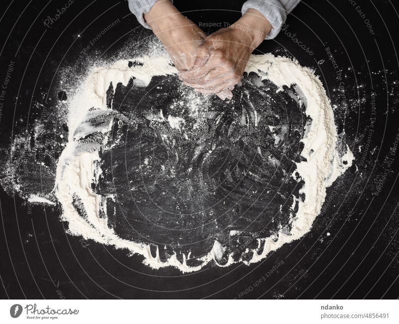 Sifted white wheat flour on a black table and two female hands, top view. cooking at home baker bakery baking bread cuisine dough food heap holding indoor