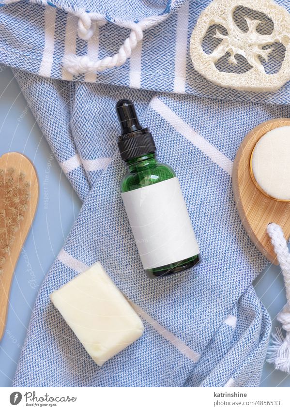 Dropper bottle on blue bath towel and skin care accessories, mockup Cosmetics pipetta homemade hair care white natural eco friendly top view serum essential oil