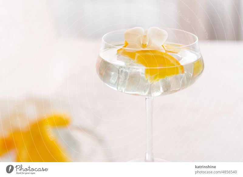 Transparent cocktail with ice cubes in a glass decorated with slices of orange close up champagne coupe pieces Tropical drink bar orchid flower Summer Nobody
