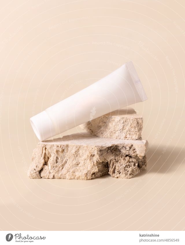 White plastic cream tube on stone on light yellow close up, Mockup mockup white pastel negative space copy space Brand packaging natural cosmetics travertine