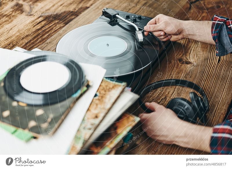 Man listening to music from vinyl record. Playing music from analog disk on turntable player. Enjoying music from old collection. Retro and vintage album retro