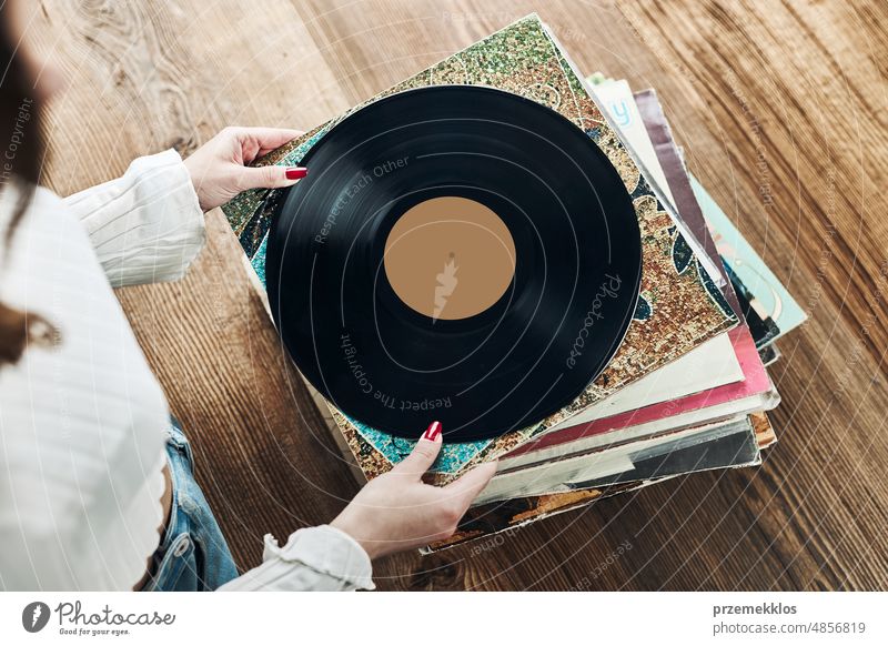 Playing vinyl records. Listening to music from vinyl record player. Retro and vintage music style. Woman holding analog LP record album. Music passion listening