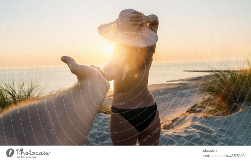 Couple holding hands and walking to the beach at sunset, woman with straw hat and beach dress - First person perspective couple first summer travel sea baltic