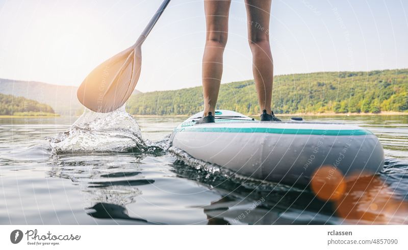 Stand up paddle boarding on a quiet lake at summer, close-up of legs stand paddleboard sport water adventure sup woman water sport surf recreation travel fun