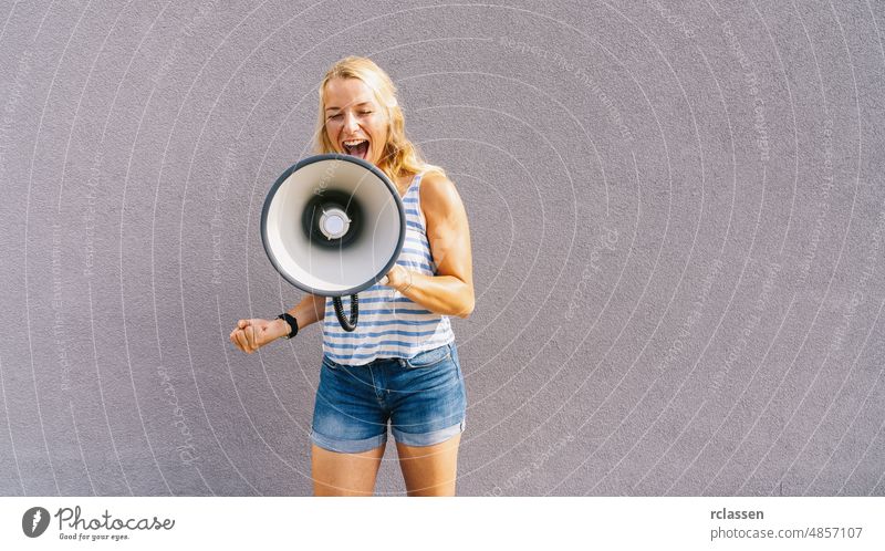 young blond woman shouting on a megaphone. copyspace for your individual text. business concept image climate public girl change speaker loud loudspeaker