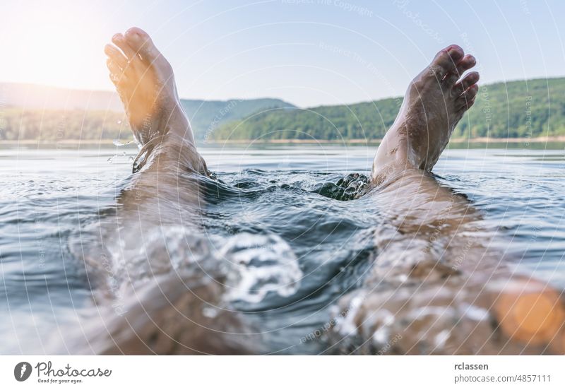 Happy man having fun and splashing water with his feet on a lake happy summer travel chilling nature dip holiday outside pond sea wet swim dipping relax canada