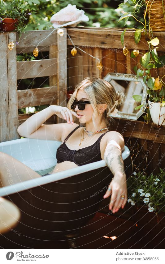 Woman in bath on patio woman bathtub water skin care terrace wellbeing chill routine style sunglasses appearance feminine rest summer charming lady summertime