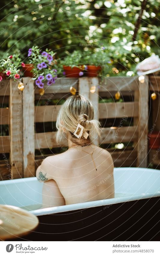 Unrecognizable woman sitting in bathtub water patio skin care terrace wellbeing routine topless chill style appearance rest wash summer charming lady summertime