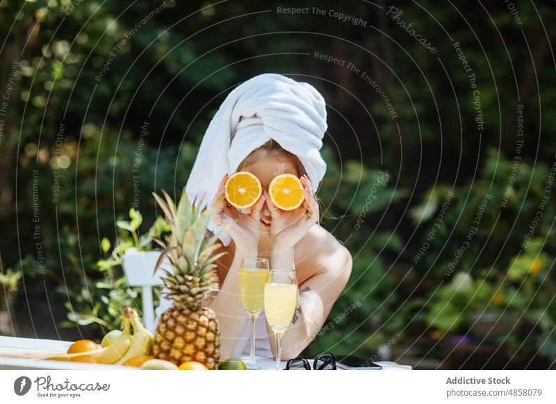 Woman covering eyes with oranges on terrace woman towel morning patio fruit cover eyes breakfast citrus juice beverage drink feminine summer glass table female
