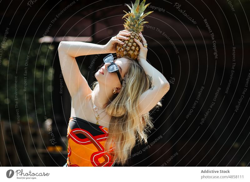 Woman with pineapple on head woman terrace style fruit healthy food sunglasses exotic tropical natural vitamin trendy building summer ripe organic fresh eyewear