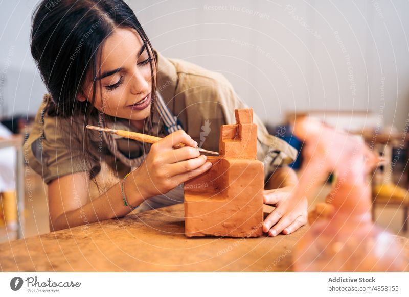 Young craftswoman carving geometric shape from clay carve geometry studio portrait smile creative handmade female young hispanic ethnic table artisan hobby