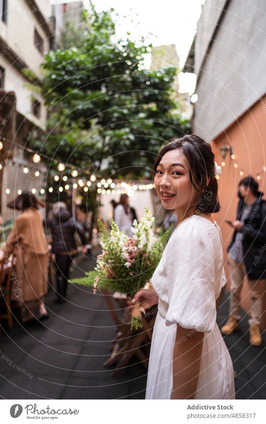 Young ethnic bride with bouquet of flowers woman wedding smile celebrate marriage street fiancee asian chinese bloom blossom toothy smile happy cheerful delight