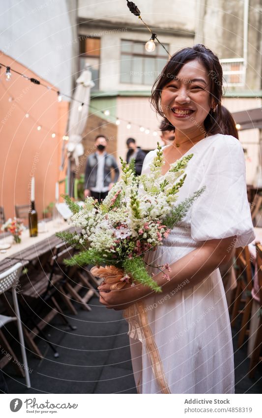 Young ethnic bride with bouquet of flowers woman wedding smile celebrate marriage street fiancee asian bloom blossom toothy smile happy cheerful delight joy